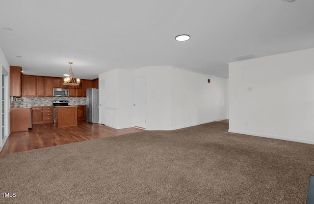 unfurnished living room featuring baseboards, a chandelier, visible vents, and dark colored carpet