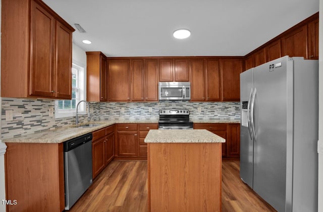 kitchen with a sink, a center island, stainless steel appliances, and wood finished floors
