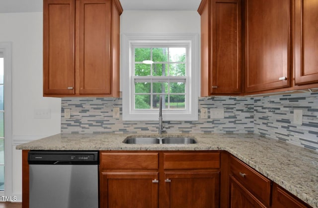 kitchen featuring stainless steel dishwasher, light stone countertops, a sink, and tasteful backsplash