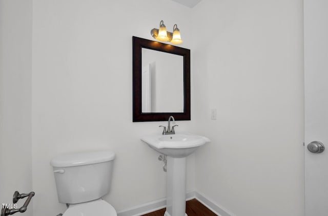 bathroom with baseboards, toilet, and wood finished floors