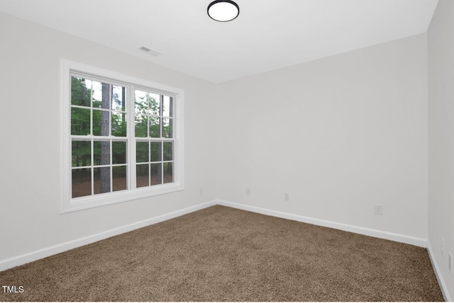 empty room featuring baseboards, visible vents, and dark carpet