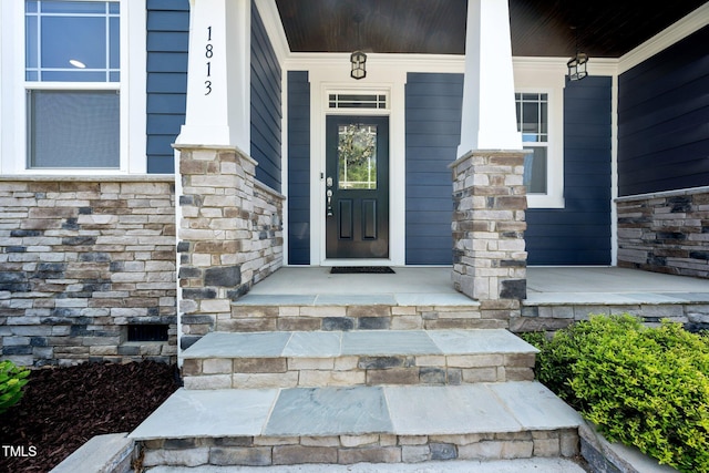 view of exterior entry with covered porch and stone siding