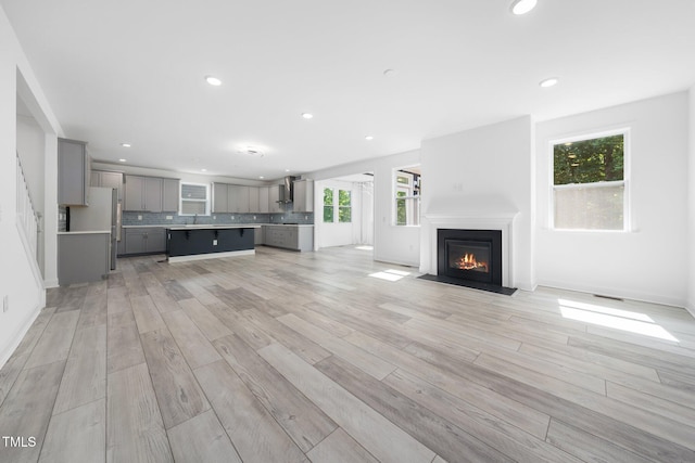 unfurnished living room featuring a fireplace with flush hearth, recessed lighting, and light wood-style flooring