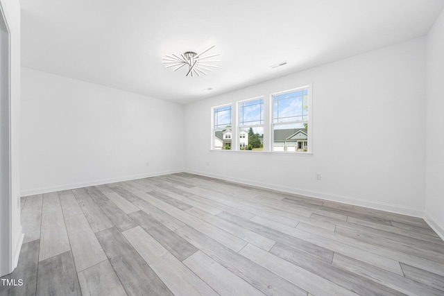 empty room with baseboards, light wood-style flooring, and visible vents