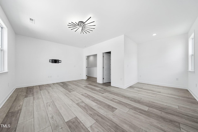 empty room featuring visible vents, light wood finished floors, and baseboards