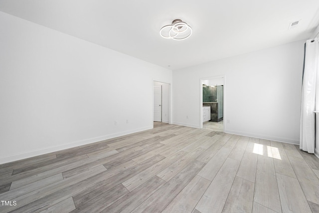 empty room featuring light wood-type flooring, baseboards, and visible vents