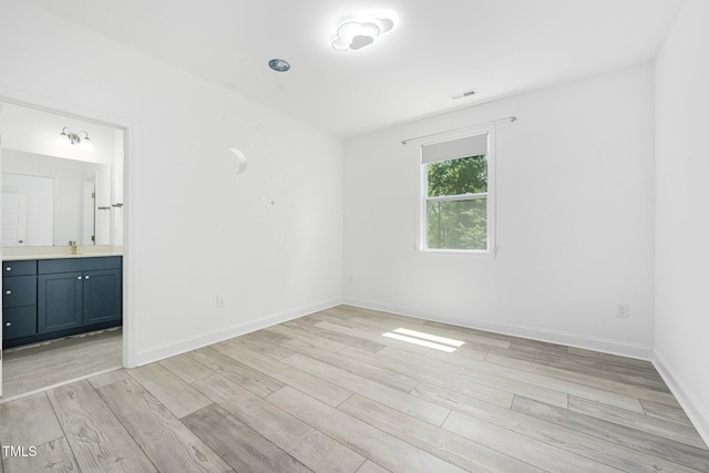 unfurnished room featuring baseboards, visible vents, and light wood-style flooring