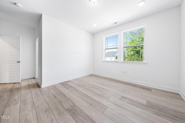 empty room with visible vents, baseboards, and light wood-type flooring