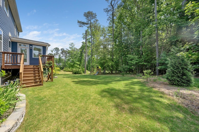 view of yard with a playground, stairs, and a deck