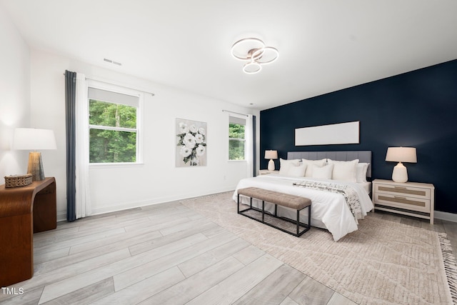 1813 Lost Creek Ct, Apex, NC 27539 - bedroom featuring multiple windows, an accent wall, and wood finished floors