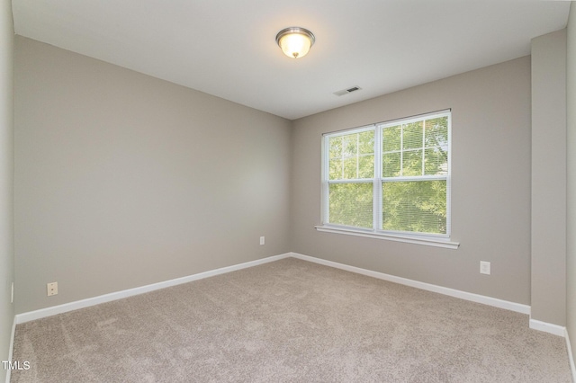 unfurnished room featuring baseboards, visible vents, and carpet