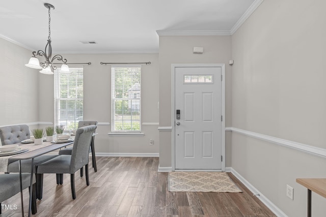 foyer featuring crown molding, a chandelier, baseboards, wood finished floors, and visible vents