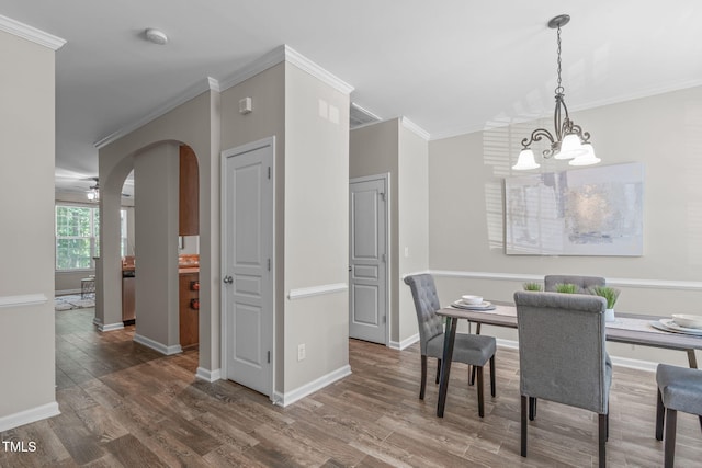dining room with crown molding, arched walkways, a chandelier, and wood finished floors