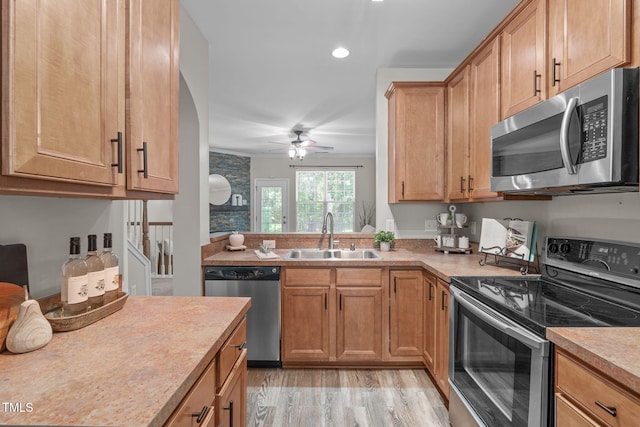 kitchen featuring a ceiling fan, light countertops, a sink, light wood finished floors, and stainless steel appliances