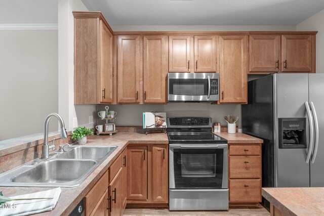 kitchen featuring a sink, appliances with stainless steel finishes, ornamental molding, and light countertops
