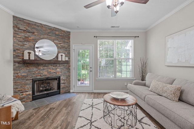 living room featuring ceiling fan, a fireplace, wood finished floors, visible vents, and ornamental molding