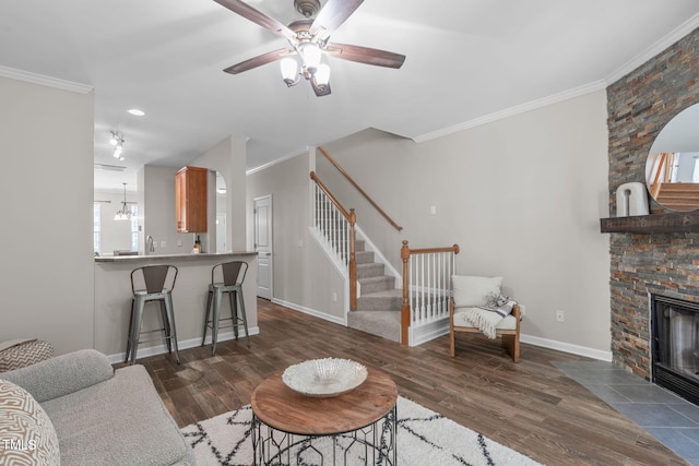 living room with a ceiling fan, dark wood finished floors, ornamental molding, and stairway