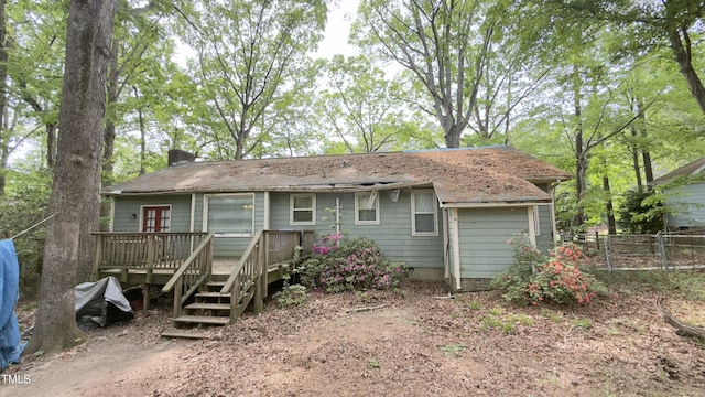 rear view of property with a wooden deck, a chimney, and fence