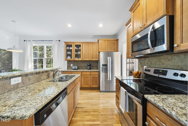 20 Paddy Ln, Youngsville, NC 27596 - kitchen with stainless steel appliances, a sink, brown cabinetry, light wood-style floors, and ornamental molding