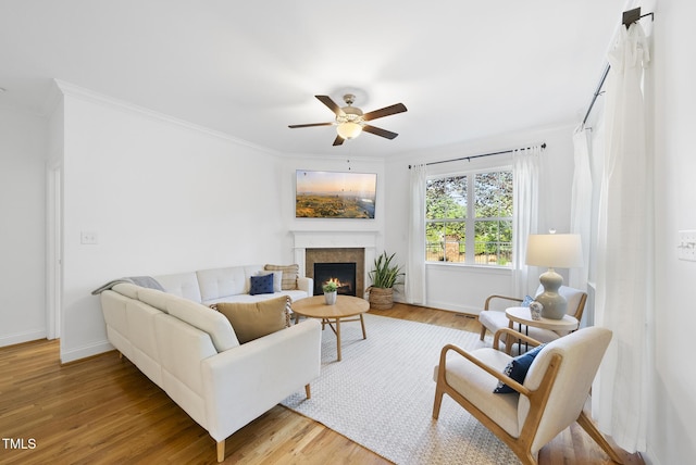 20 Paddy Ln, Youngsville, NC 27596 - living room featuring a ceiling fan, crown molding, a warm lit fireplace, baseboards, and light wood-type flooring