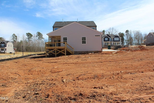 back of property with a shingled roof and a deck