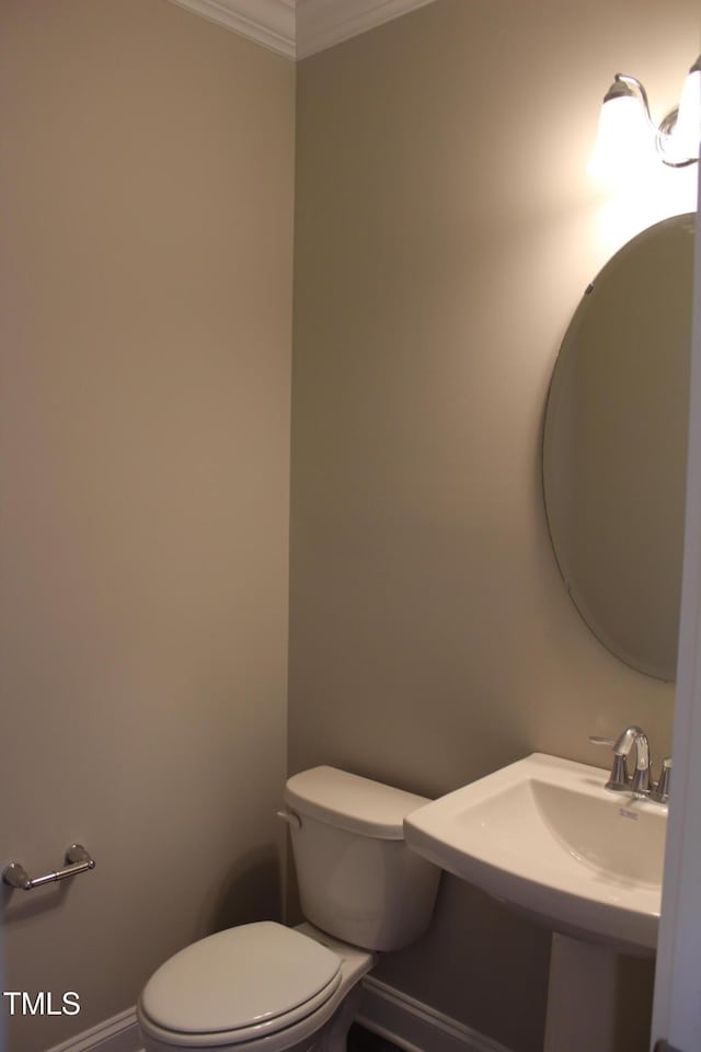 bathroom with a sink, baseboards, ornamental molding, and toilet