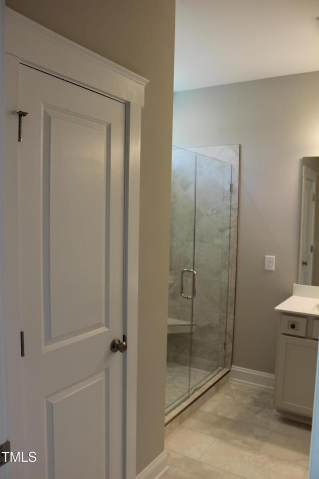 bathroom featuring vanity, baseboards, and a shower stall