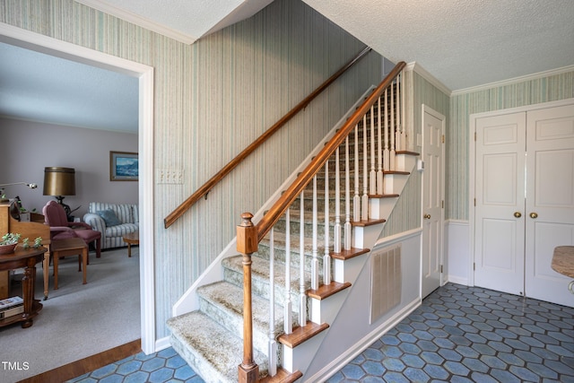 stairway featuring crown molding, wallpapered walls, and a textured ceiling