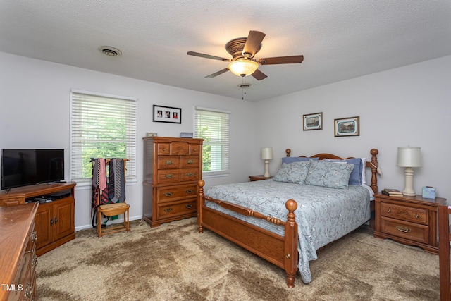 bedroom featuring light colored carpet, a ceiling fan, a textured ceiling, and visible vents