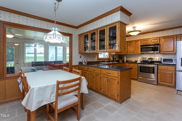 kitchen with ornamental molding, wallpapered walls, brown cabinets, a sink, and appliances with stainless steel finishes
