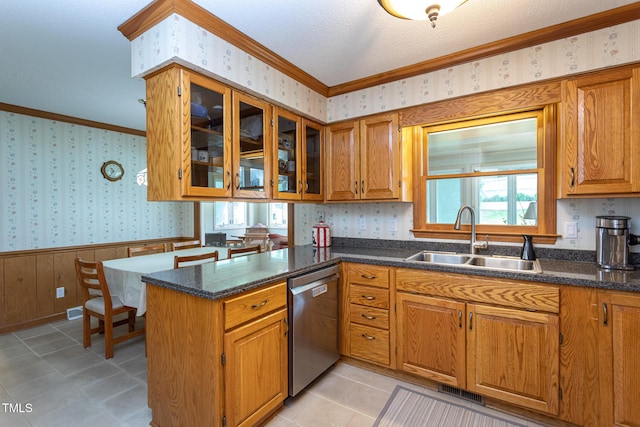 kitchen featuring stainless steel dishwasher, wainscoting, brown cabinets, a sink, and wallpapered walls
