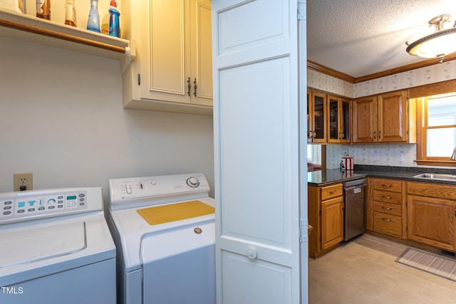 clothes washing area with ornamental molding, a textured ceiling, a sink, cabinet space, and independent washer and dryer