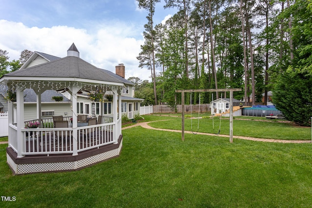 view of yard with a gazebo, a fenced backyard, a shed, and an outbuilding