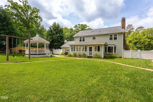 back of house featuring a yard, a gazebo, a chimney, and a fenced backyard