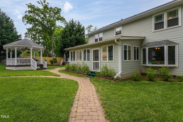 rear view of house featuring a gazebo, a lawn, and fence