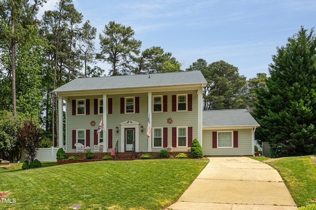 neoclassical home featuring a porch, fence, driveway, and a front yard
