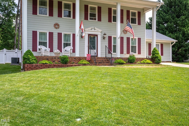 neoclassical / greek revival house with fence, covered porch, a shingled roof, and a front lawn