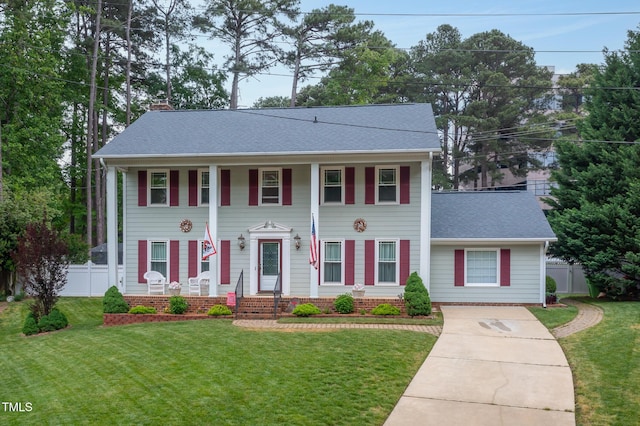 view of front of home with fence, driveway, a chimney, and a front yard