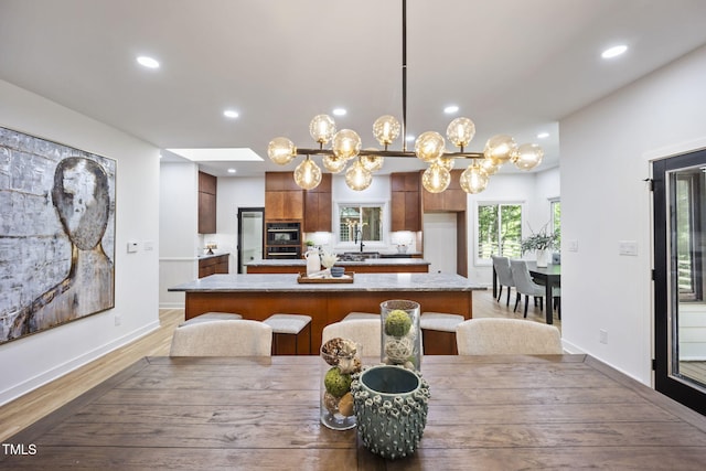 dining space with recessed lighting, baseboards, a notable chandelier, and light wood-style flooring