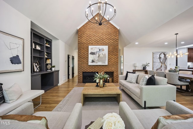 living room with an inviting chandelier, lofted ceiling, wood finished floors, and a fireplace
