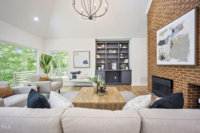 living room featuring an inviting chandelier, a fireplace, high vaulted ceiling, recessed lighting, and wood finished floors