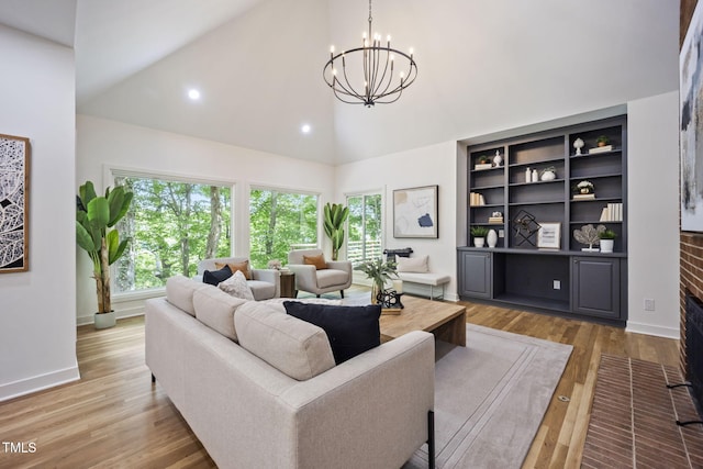 living room with high vaulted ceiling, an inviting chandelier, a wealth of natural light, and light wood-style flooring