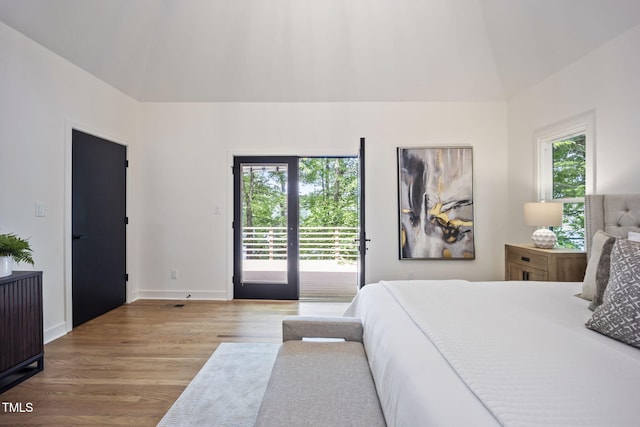 bedroom featuring access to outside, baseboards, wood finished floors, and high vaulted ceiling