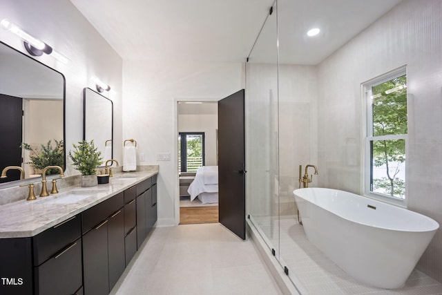 bathroom with connected bathroom, double vanity, a freestanding tub, and a sink