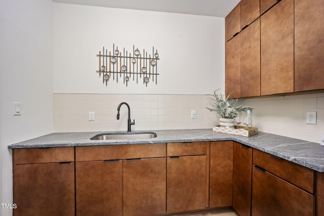 kitchen featuring a sink, brown cabinetry, and backsplash