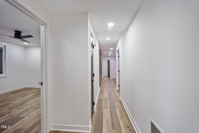 hall with light wood-style floors, baseboards, recessed lighting, and visible vents