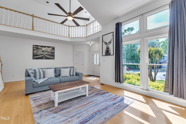 living room featuring baseboards, light wood finished floors, and a towering ceiling
