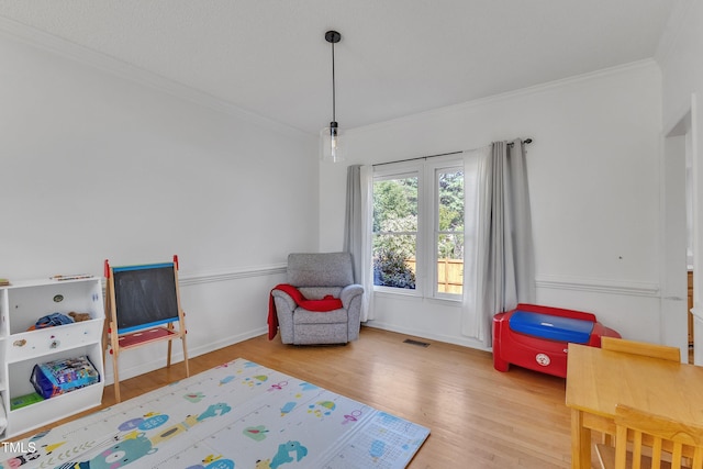 recreation room featuring visible vents, ornamental molding, baseboards, and wood finished floors