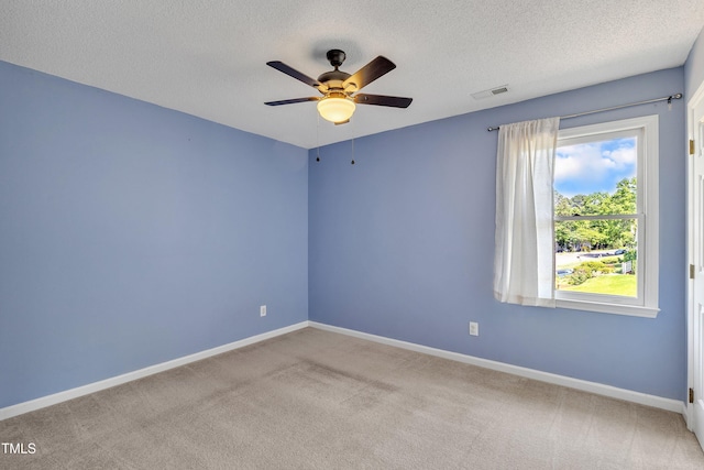 carpeted empty room with baseboards, a ceiling fan, a textured ceiling, and visible vents