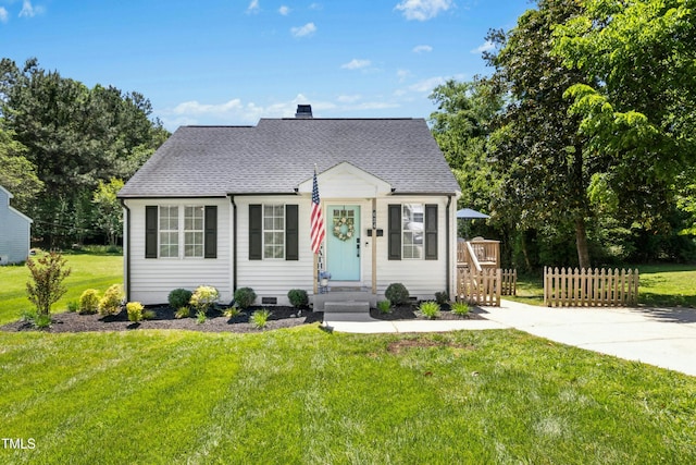 cape cod house with fence, a shingled roof, and a front yard